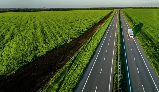 Truck driving down a highway through a field